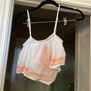 White cropped top with orange stitching.
